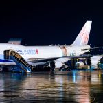 Avião cargueiro da China Airlines sendo carregado à noite em um aeroporto, com operações de pista ao redor.