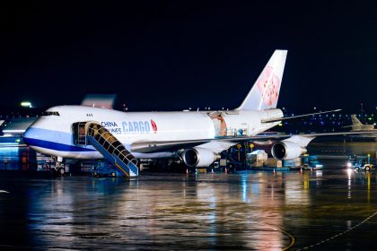 Avião cargueiro da China Airlines sendo carregado à noite em um aeroporto, com operações de pista ao redor.