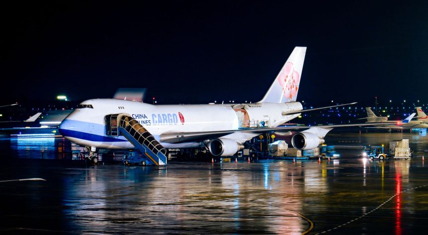Avião cargueiro da China Airlines sendo carregado à noite em um aeroporto, com operações de pista ao redor.