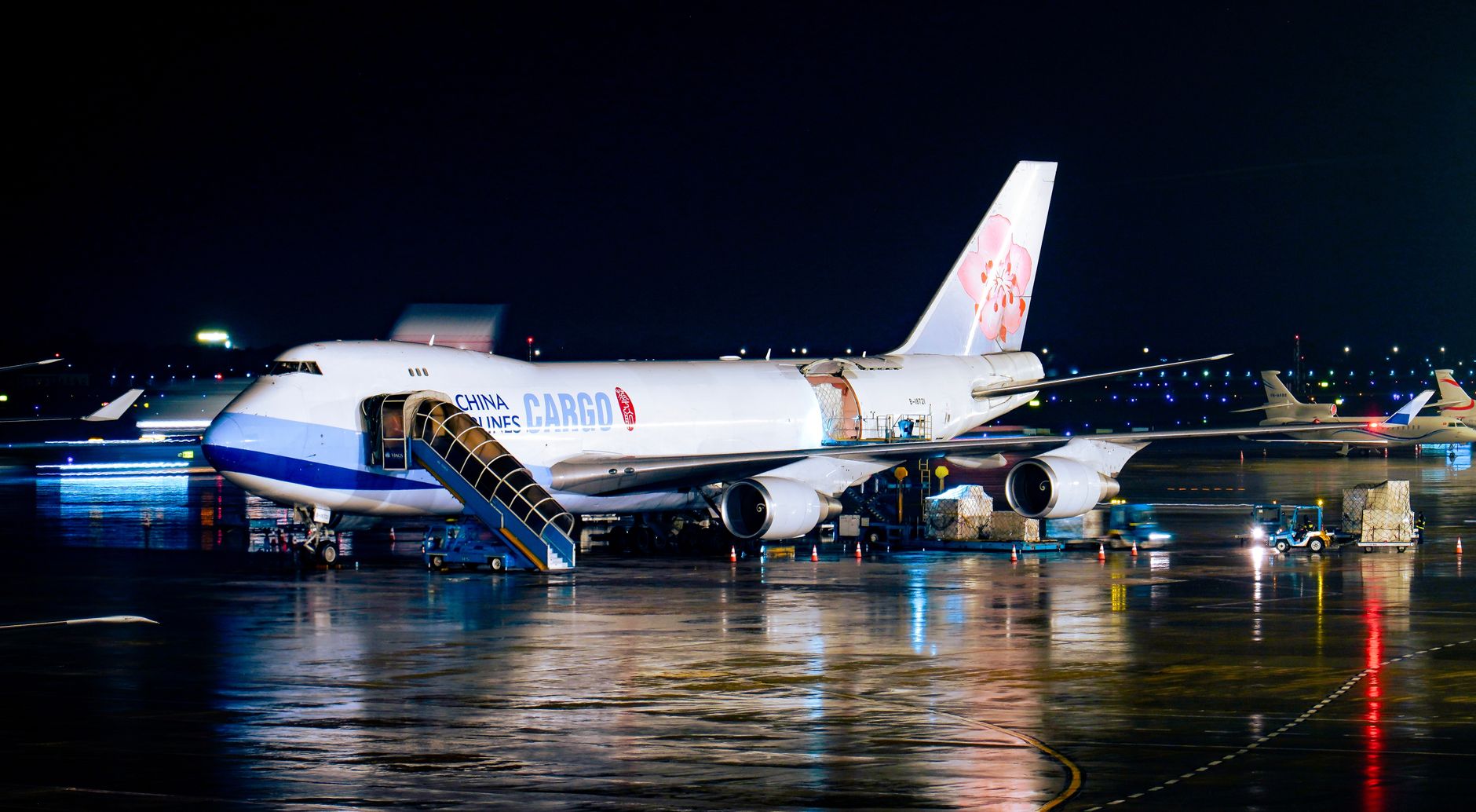 Avião cargueiro da China Airlines sendo carregado à noite em um aeroporto, com operações de pista ao redor.