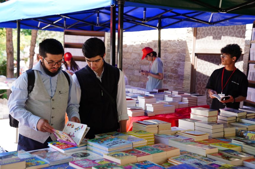 Pessoas consultam livros em uma feira literária ao ar livre.