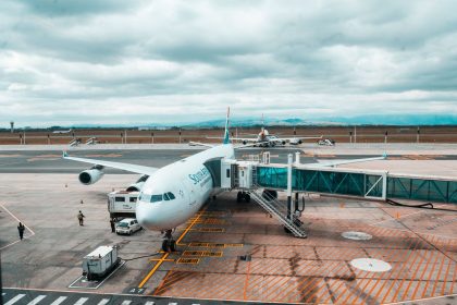Avião comercial conectado a uma ponte de embarque em um terminal aeroportuário.