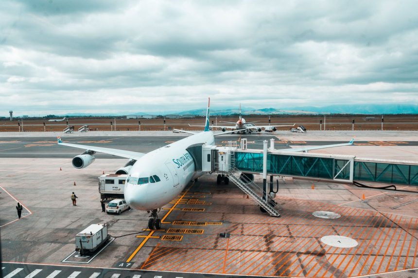 Avião comercial conectado a uma ponte de embarque em um terminal aeroportuário.