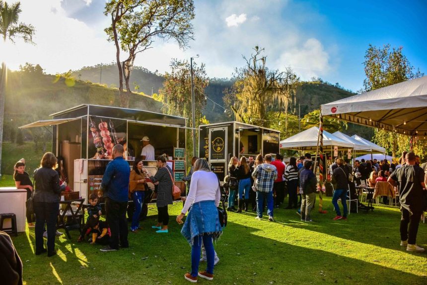 Público circula entre barracas de comida em um festival ao ar livre realizado em um parque brasileiro.